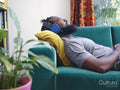 Man lying on sofa,listening to music on headphones