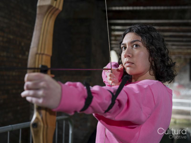 Concentrated woman aiming with bow during training