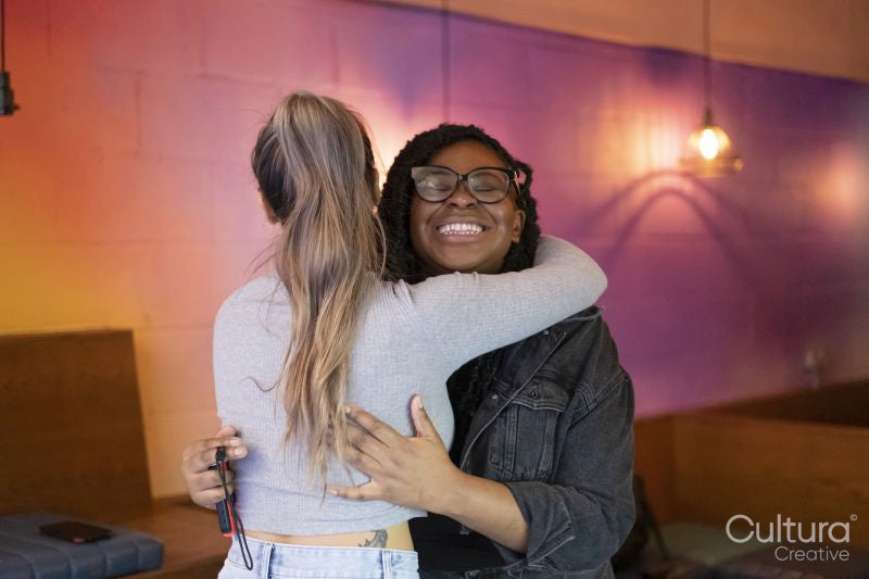 Smiling women embracing after playing video games at pub