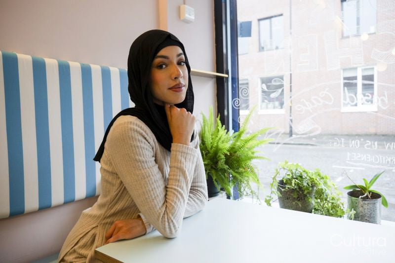 Portrait of young woman in hijab sitting in cafe