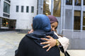 Two women wearing hijabs hugging in street