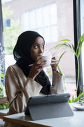 Young woman in hijab working on tablet in cafe
