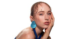 Studio portrait of a woman in a blue dress and large blue earrings