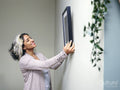 Woman hanging picture on wall