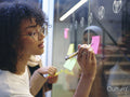 Woman writing on adhesive note in office