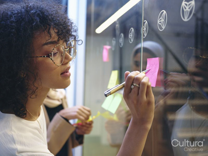 Woman writing on adhesive note in office