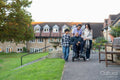 Senior man sitting in wheelchair surrounded by family and care giver outside retirement home