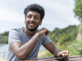 Portrait of young man using phone while sitting by lake