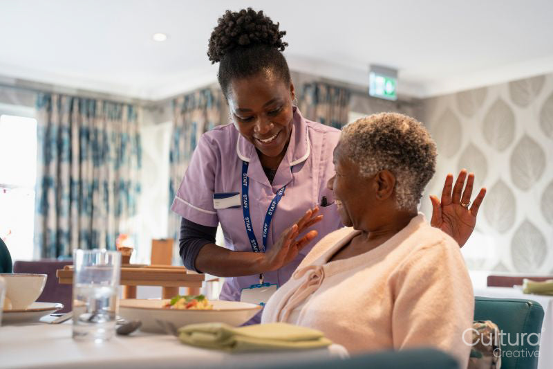 Nurse serving meal to senior woman in nursing home