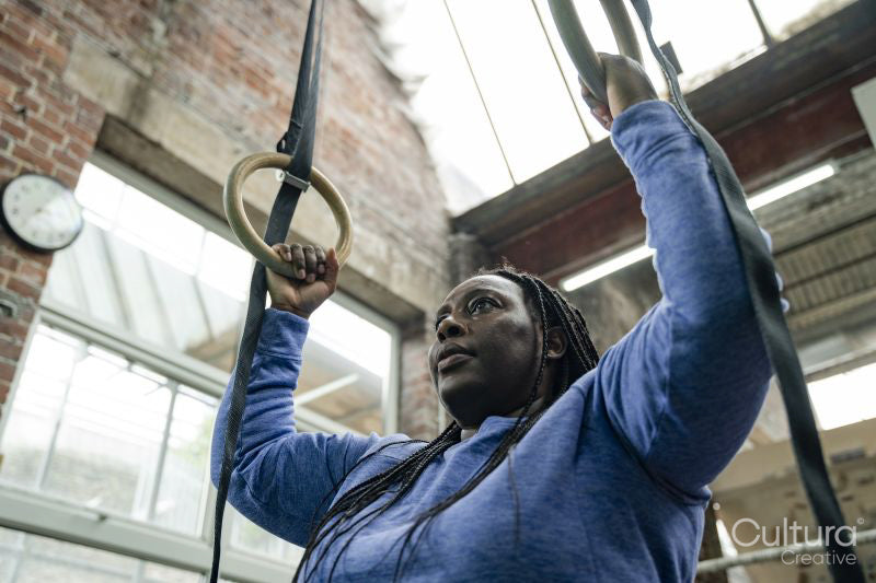Woman exercising on gymnastic rings in gym
