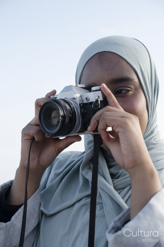 Portrait of Muslim woman photographing with analog camera