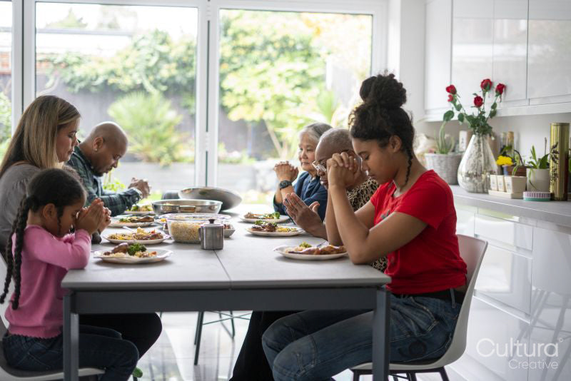 Family praying before eating dinner
