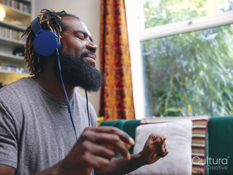 Man sitting on sofa,listening to music on headphones