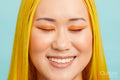 Portrait of smiling woman wearing orange make up, eyes closed