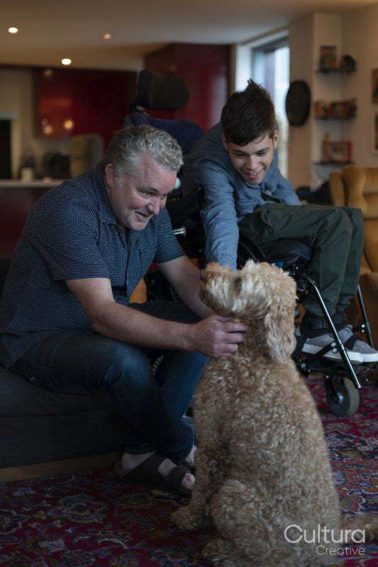 Father and disabled son cuddling dog