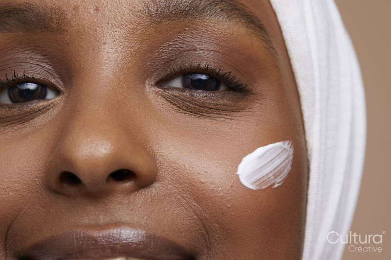 Studio portrait of young woman in white hijab applying face cream