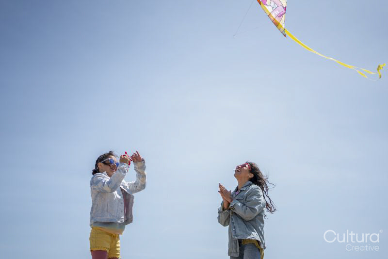 Mother and daughter flying kite on beach