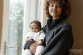 Mother holding baby daughter next to window