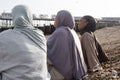 Three Muslim women sitting on beach on sunny day