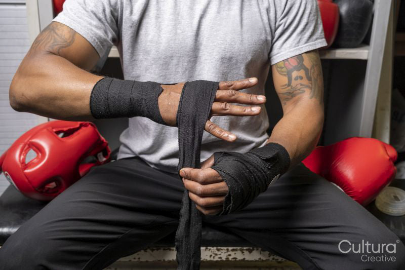 Mature man wrapping hands for boxing match, midsection