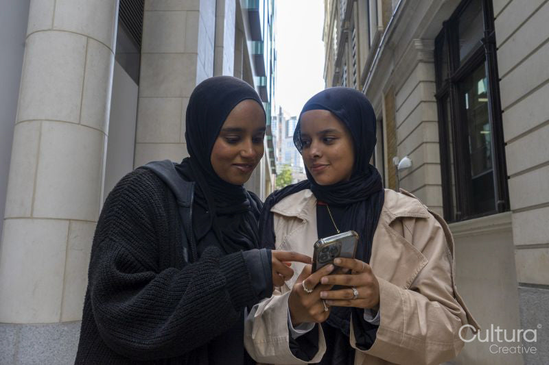 Two young women in city, looking at phone
