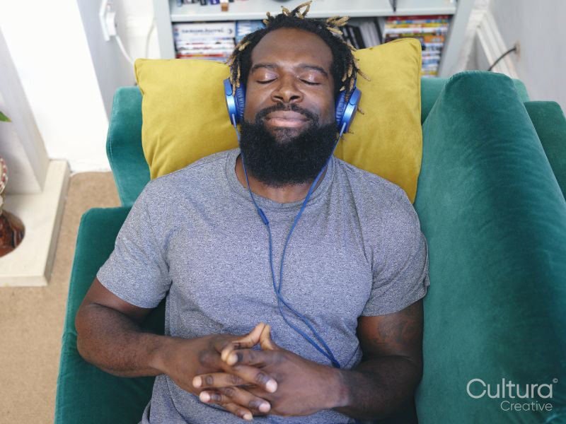 Man lying on sofa,listening to music on headphones