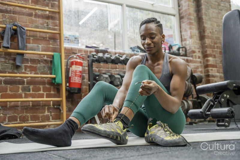 Athletic woman tying sport shoe laces at gym
