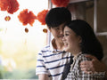 Couple hugging next to window with traditional Chinese decorations