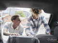 Smiling male couple loading luggage into car trunk