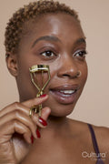 Studio portrait of woman using eyelash curler
