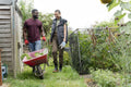 Smiling couple with vegetables in wheelbarrow in urban garden