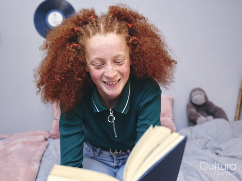 Girl reading book on bed