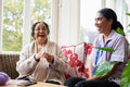 Senior woman knitting and talking to care giver in nursing home