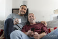 Smiling male couple watching TV at home