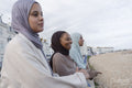 Three Muslim woman looking away while standing on beach
