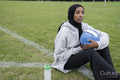 Portrait of woman in hijab sitting in soccer field