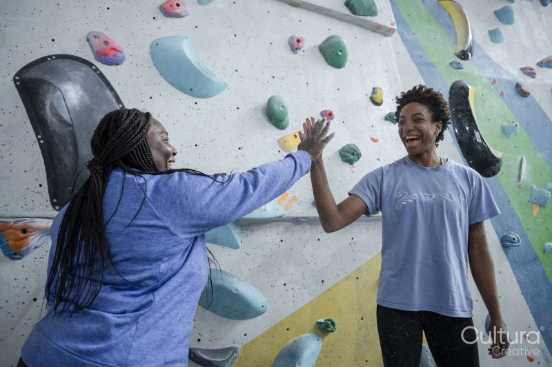 Mother and daughter giving high-five in front of climbing wall