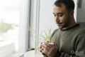 Mature man standing by window with cup of tea