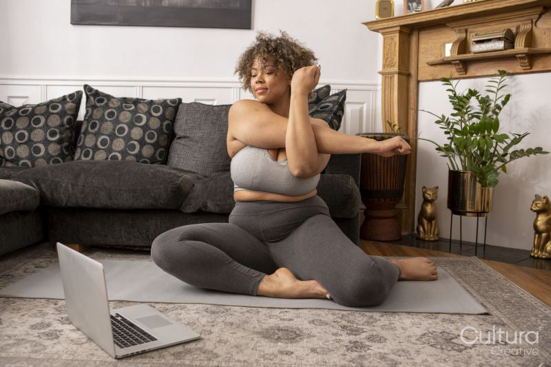 Woman exercising in living room in front of laptop