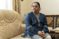 Portrait of young woman with down syndrome sitting on sofa at home