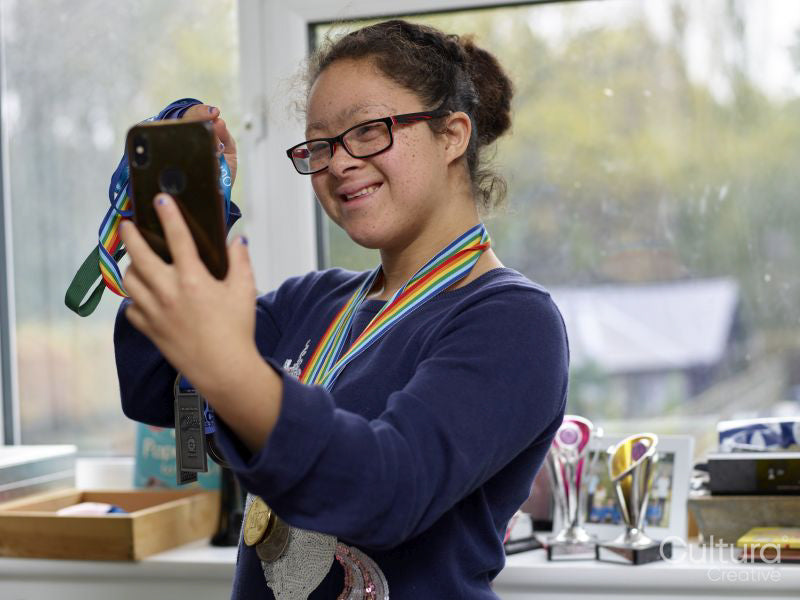 Girl with Down syndrome taking selfie with medals