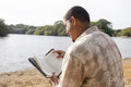 Man reading book on lakeshore