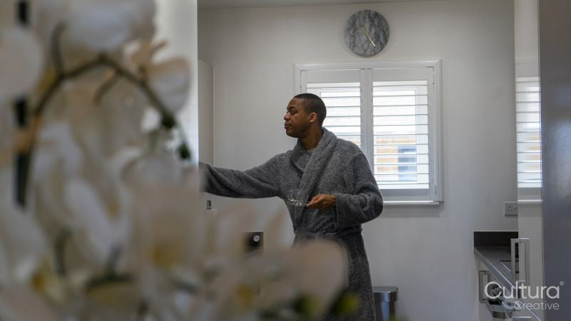 Man wearing bathrobe standing in kitchen