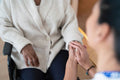 Close-up of female doctor holding senior woman's hand in doctors office