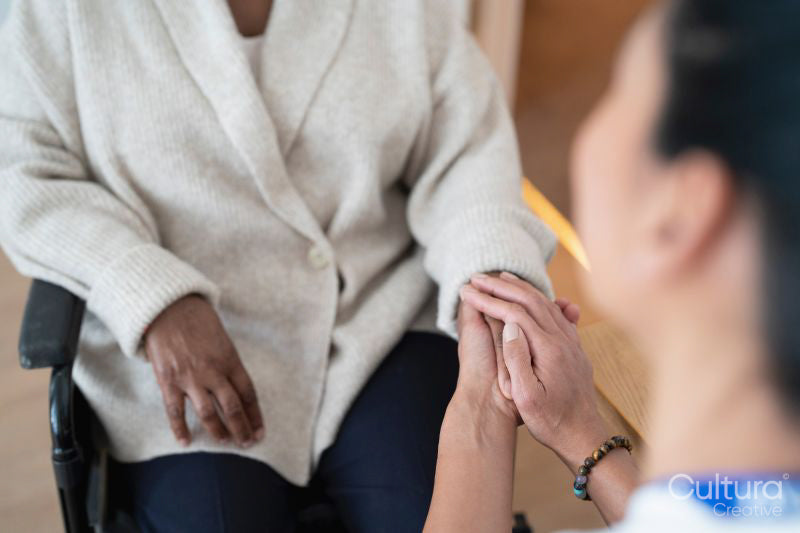 Close-up of female doctor holding senior woman's hand in doctors office