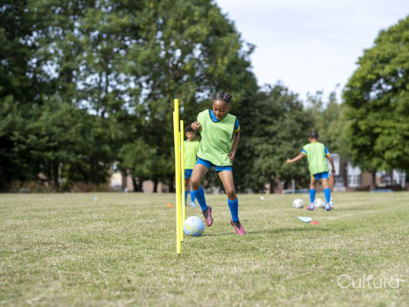 Children dressed in uniforms practicing on soccer field