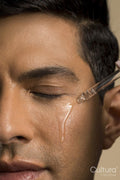 Close-up of man applying oil on face