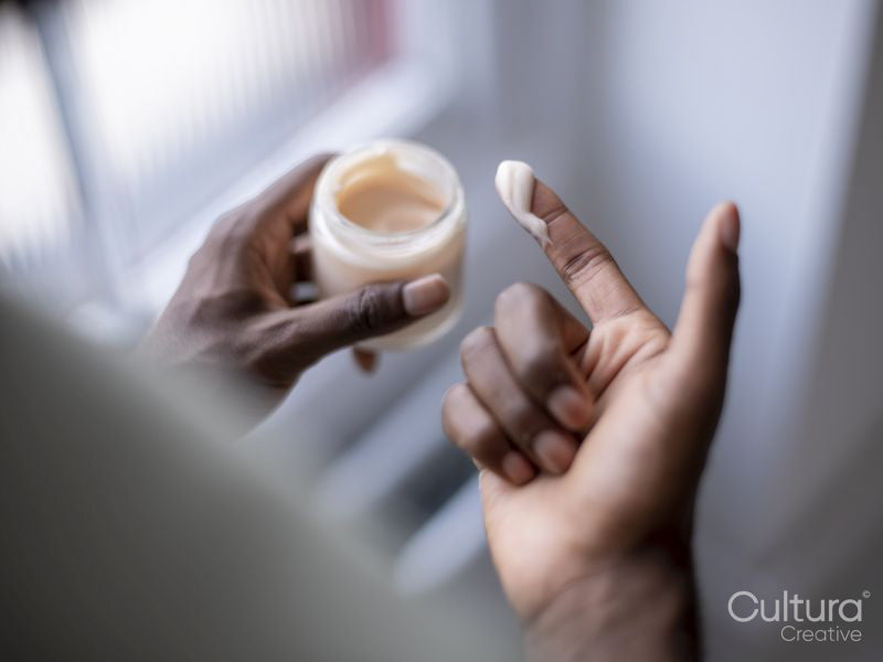 Close-up of person holding jar of moisturizer