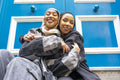 Portrait of two smiling women wearing hijabs embracing in city