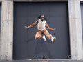 Young woman in sports clothing jumping in city